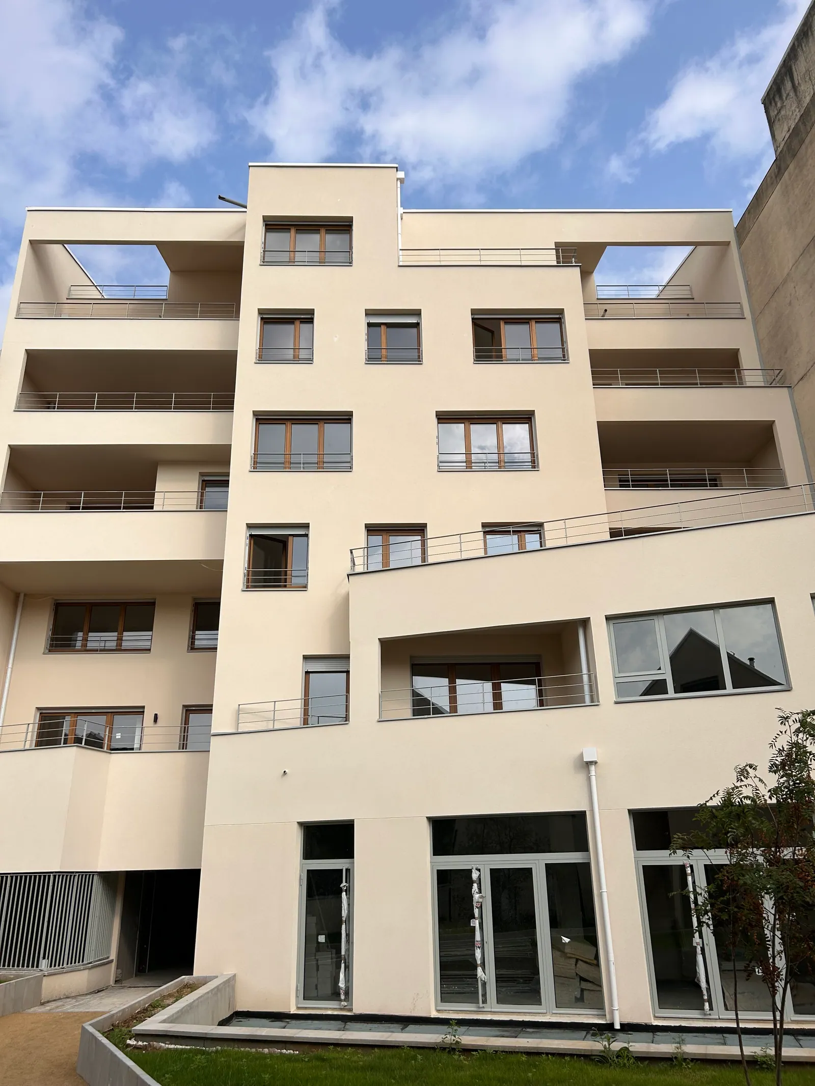 La façade sur cour : volume central en enduit clair, terrasses en gradins de part et d'autre, grandes baies vitrées en rez-de-chaussée.