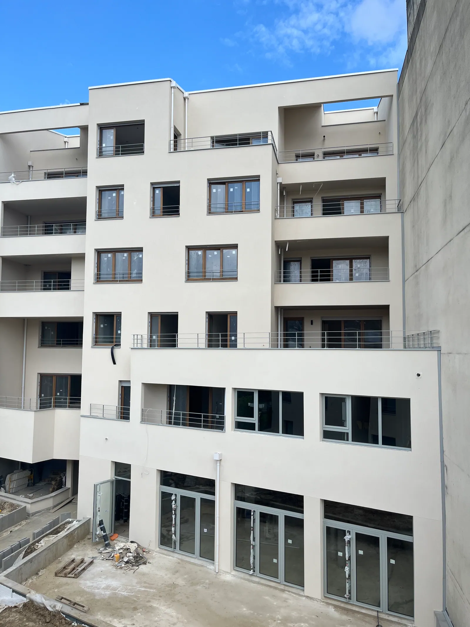La cour en fin de chantier : façades enduites terminées, terrasses en gradins, sol encore en attente d'aménagement.